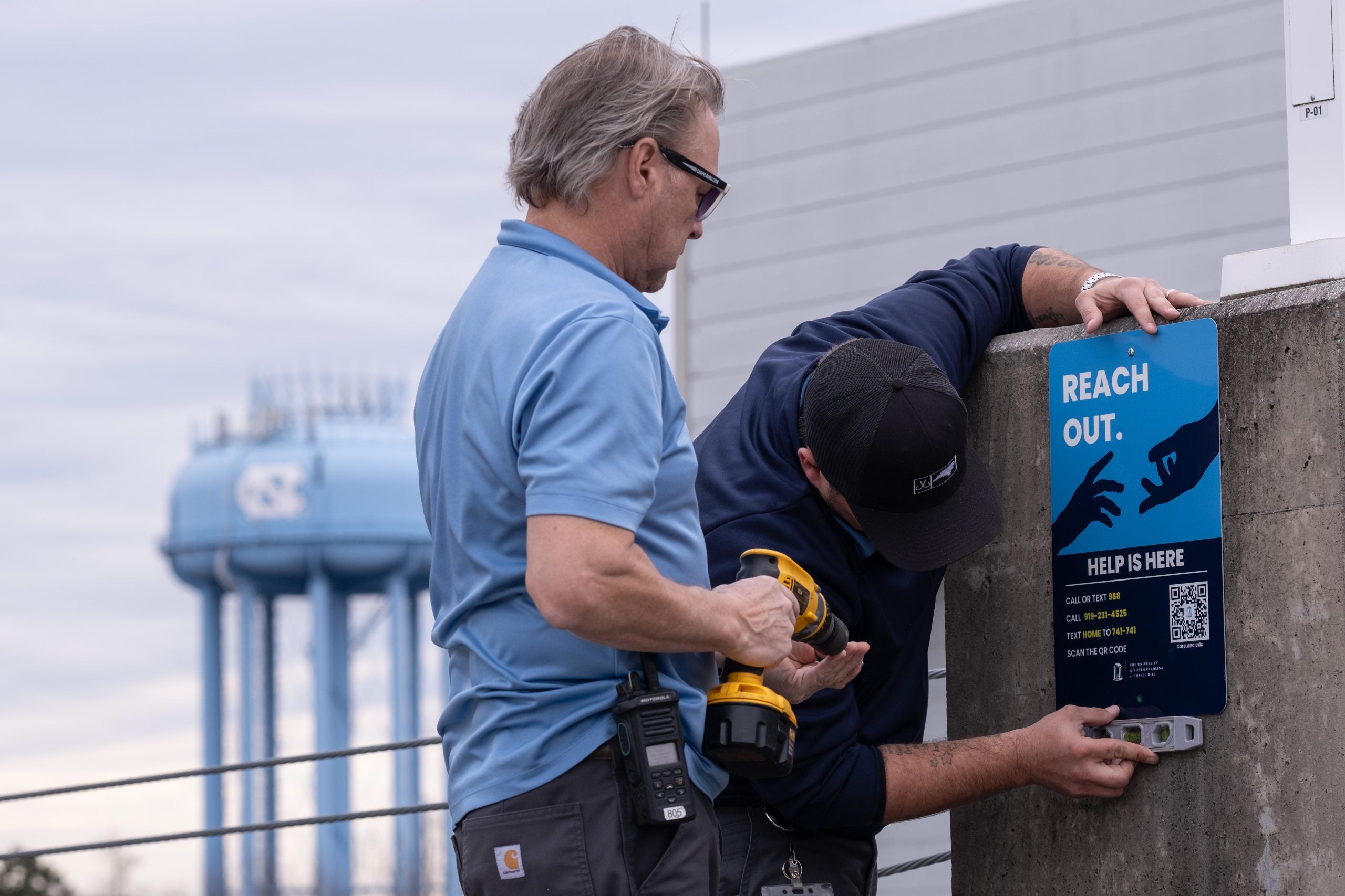 Two people installing the newly created 'reach out' signs around U.N.C. campus.