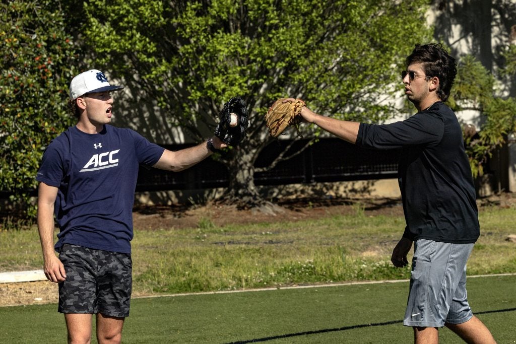 Club baseball president Cameron Wade (left) and sophomore Brendan Rosenblum meet up after a throwing drill.