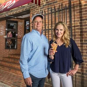 Jim Kitchen and Susan Kitchen stand outside the Yogurt Pump holding a cone of frozen yogurt.