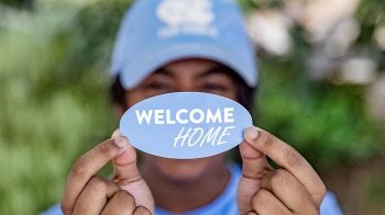 Student at UNC-Chapel Hill holding up a sticker that says 