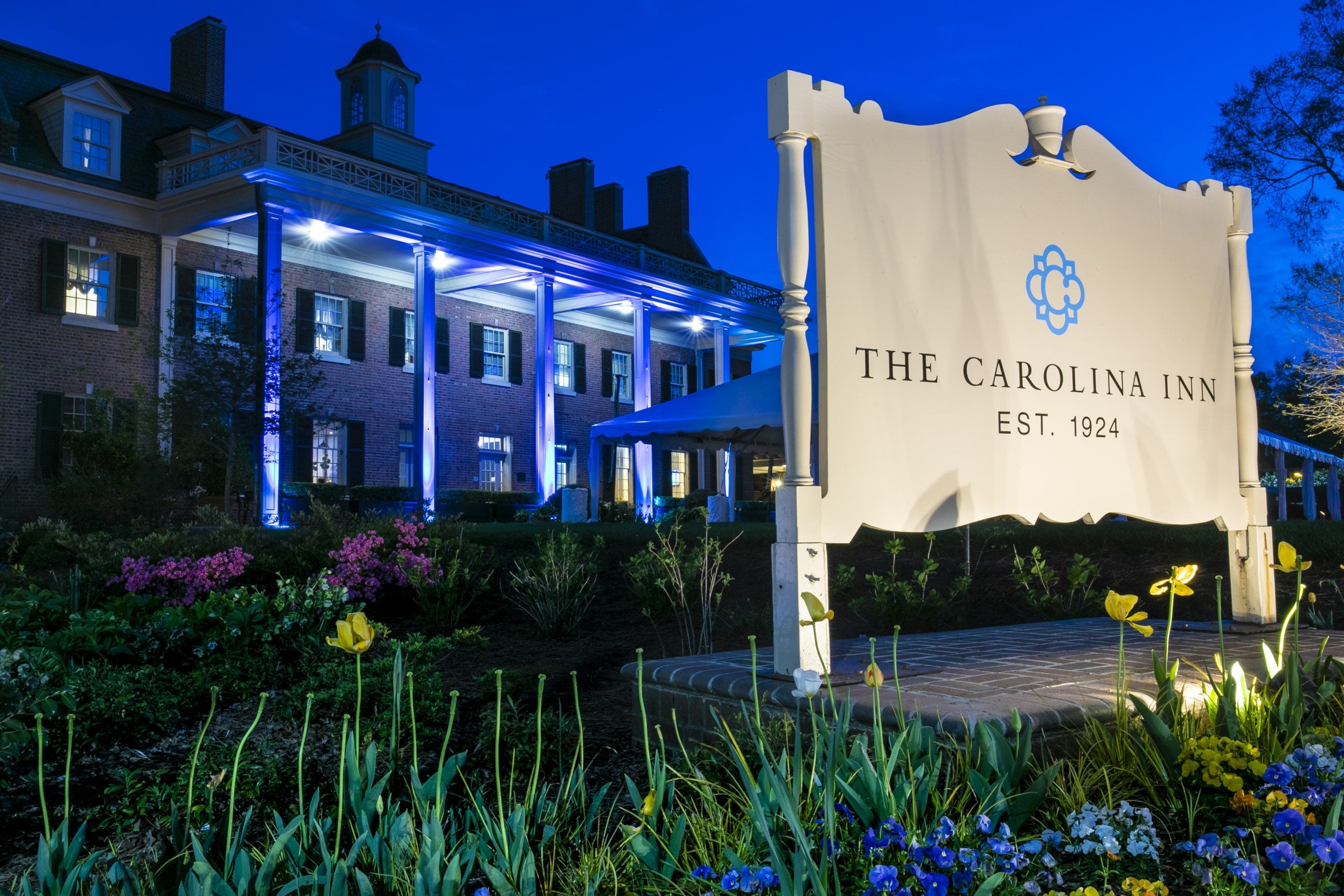 Exterior of the Carolina Inn hotel at dusk lit blue.