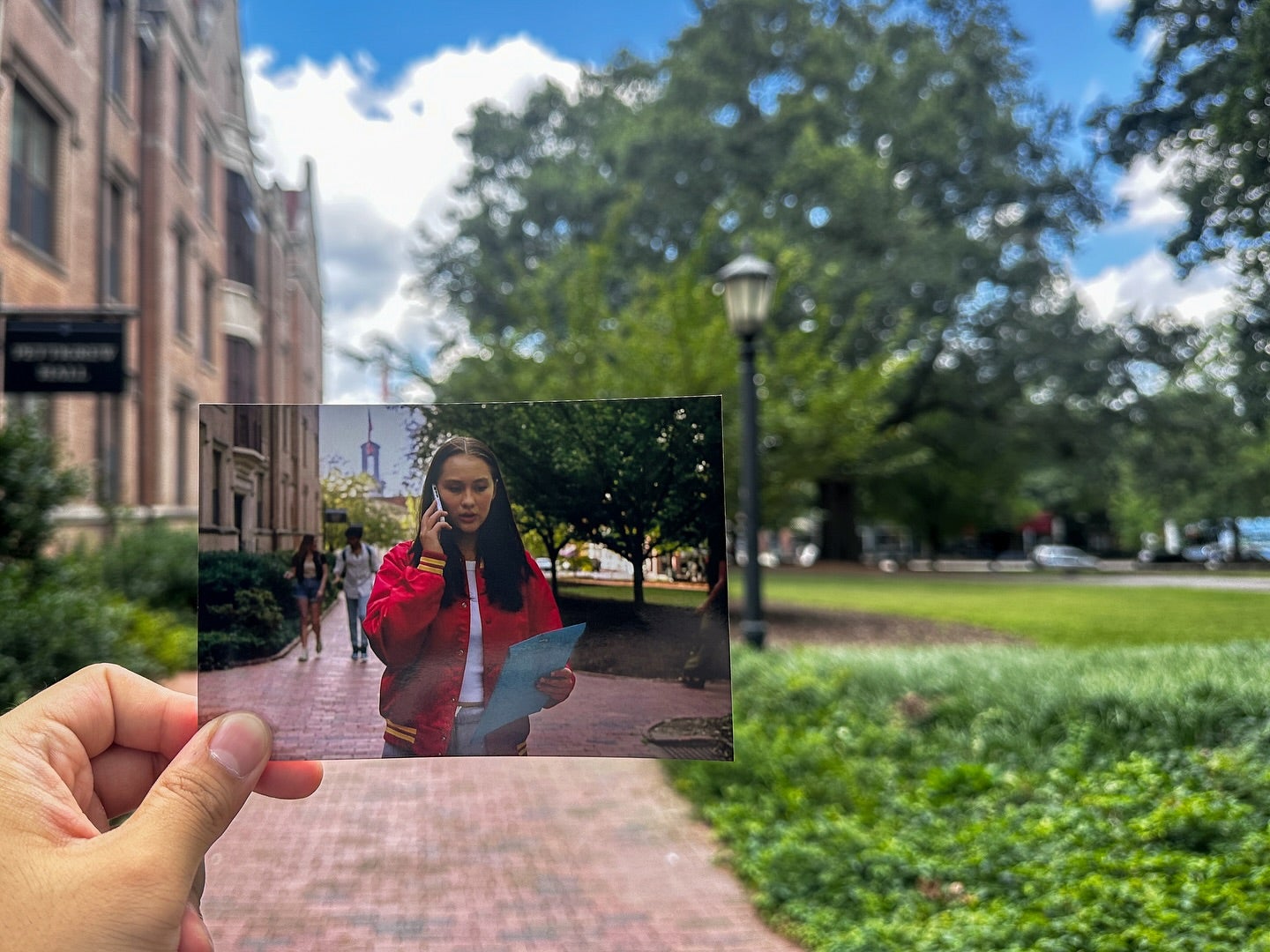 Person holding a photo of a scene from The Summer I Turned Pretty next to where it was filmed at Carolina.