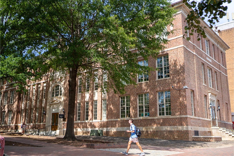 A student walking by Bingham Hall on a sunny afternoon on the campus of UNC-Chapel Hill.