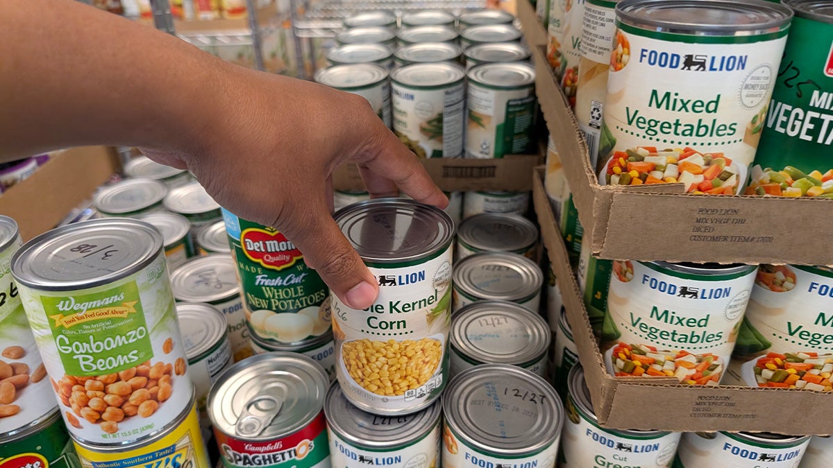 A person's hand is seen reaching for a canned food item at a food pantry on the campus of UNC-Chapel Hill.