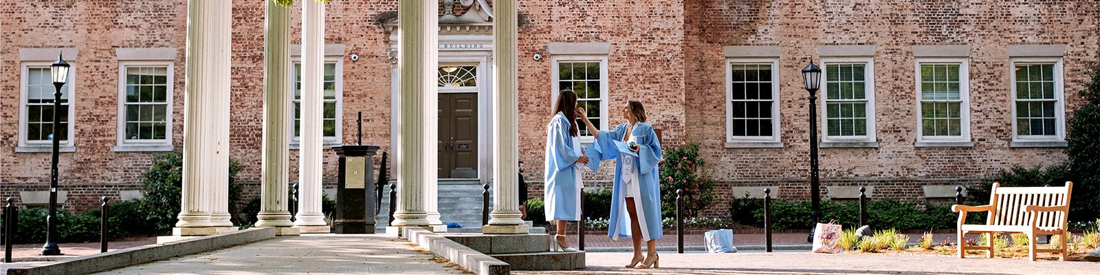Two seniors prepare to take graduation photos by the Old Well.