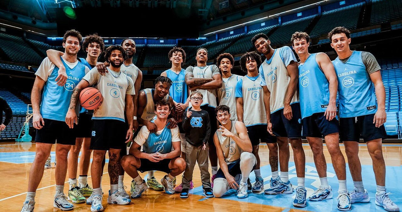 The UNC men's basketball team taking a team photo on the court of the Dean E. Smith Center with a 9-year-old boy, Colburn Dean.