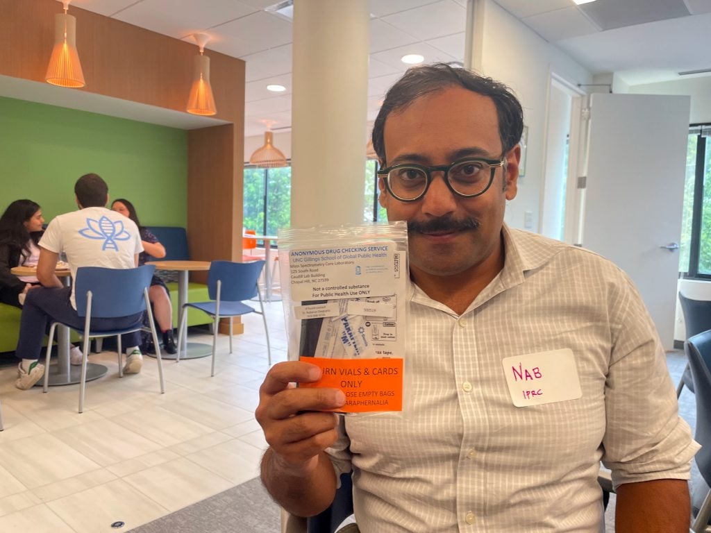 A man, Nabarun Dasgupta, smiling while posing for a picture and holding up a drug-testing kit.