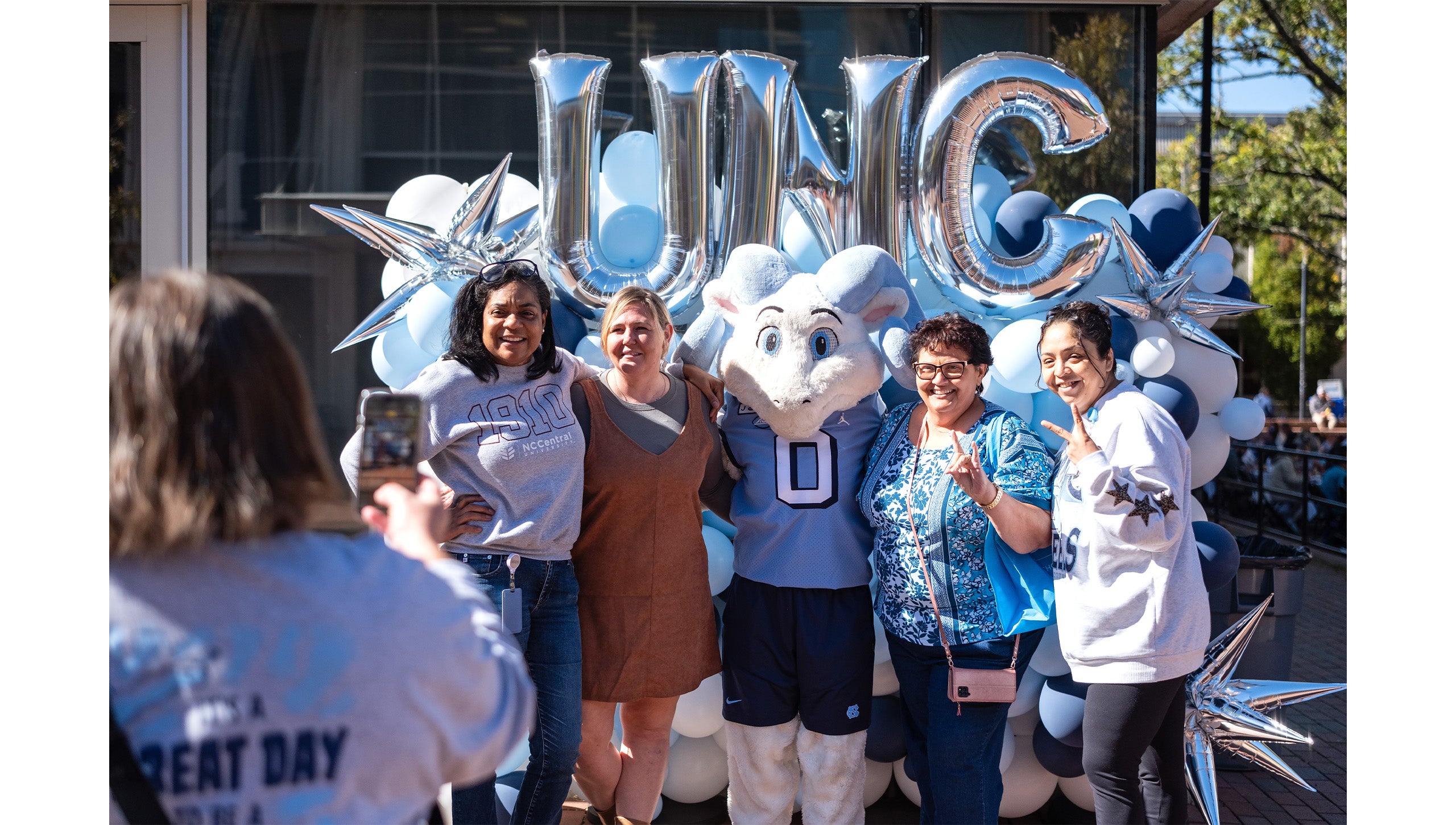 Four UNC-Chapel Hill employees taking a photo with Rameses Jr., one of Carolina's ram mascots.
