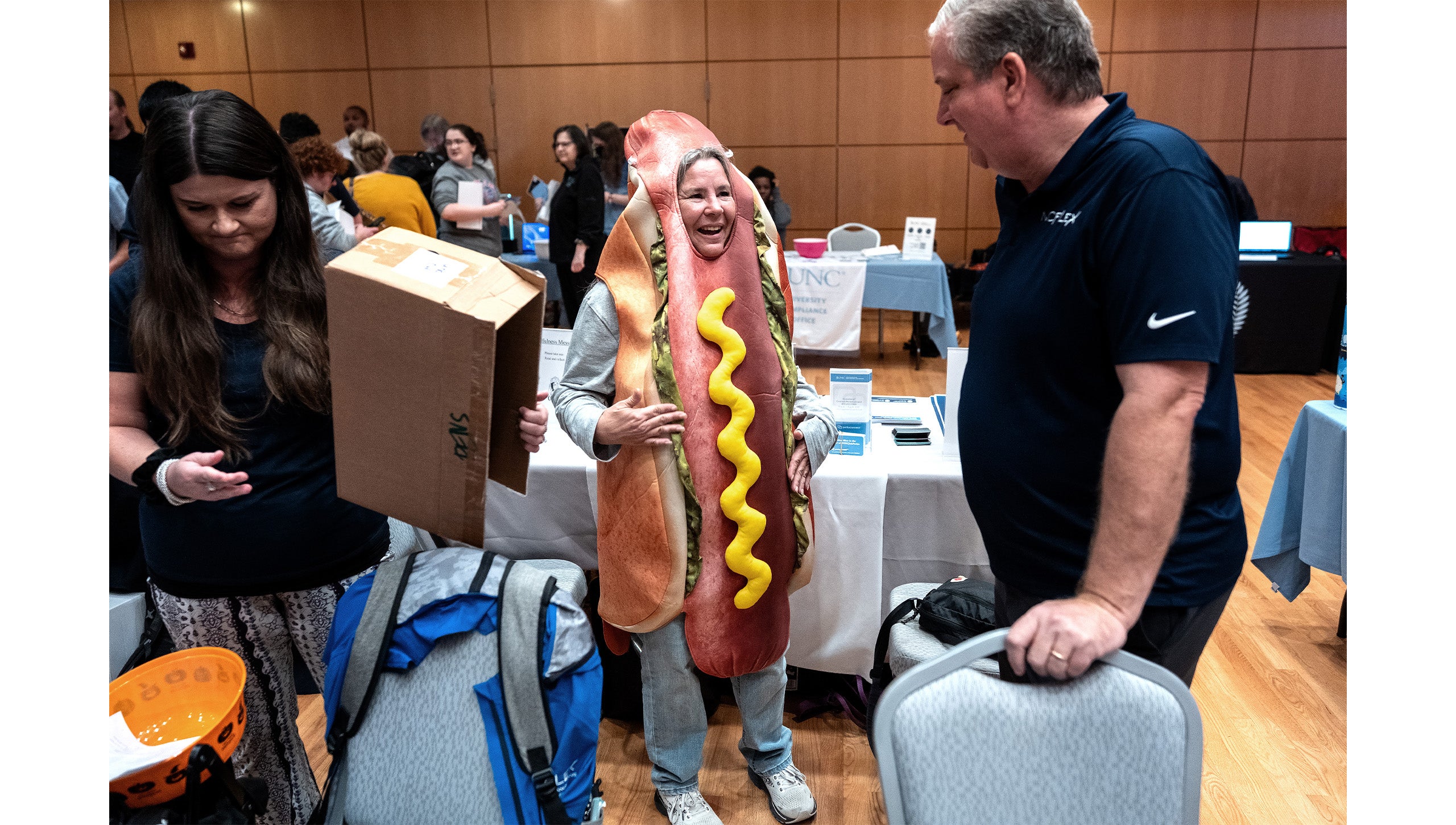 A woman in a hotdog suit talking to a man.
