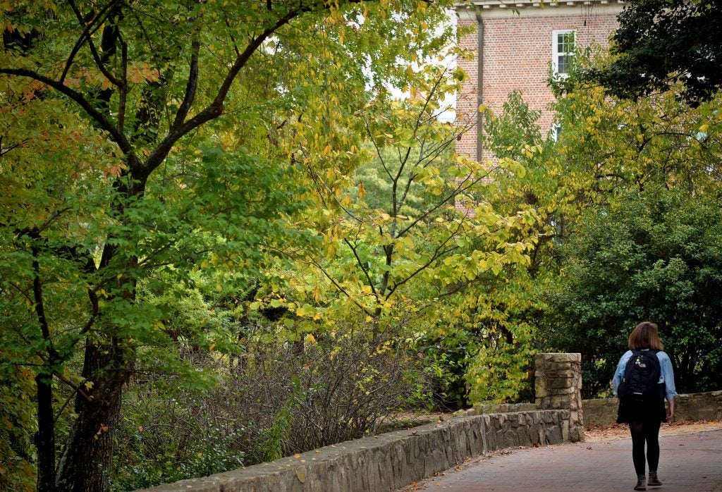 Student walking by Coker Arboretum on the campus of U.N.C Chapel Hill.