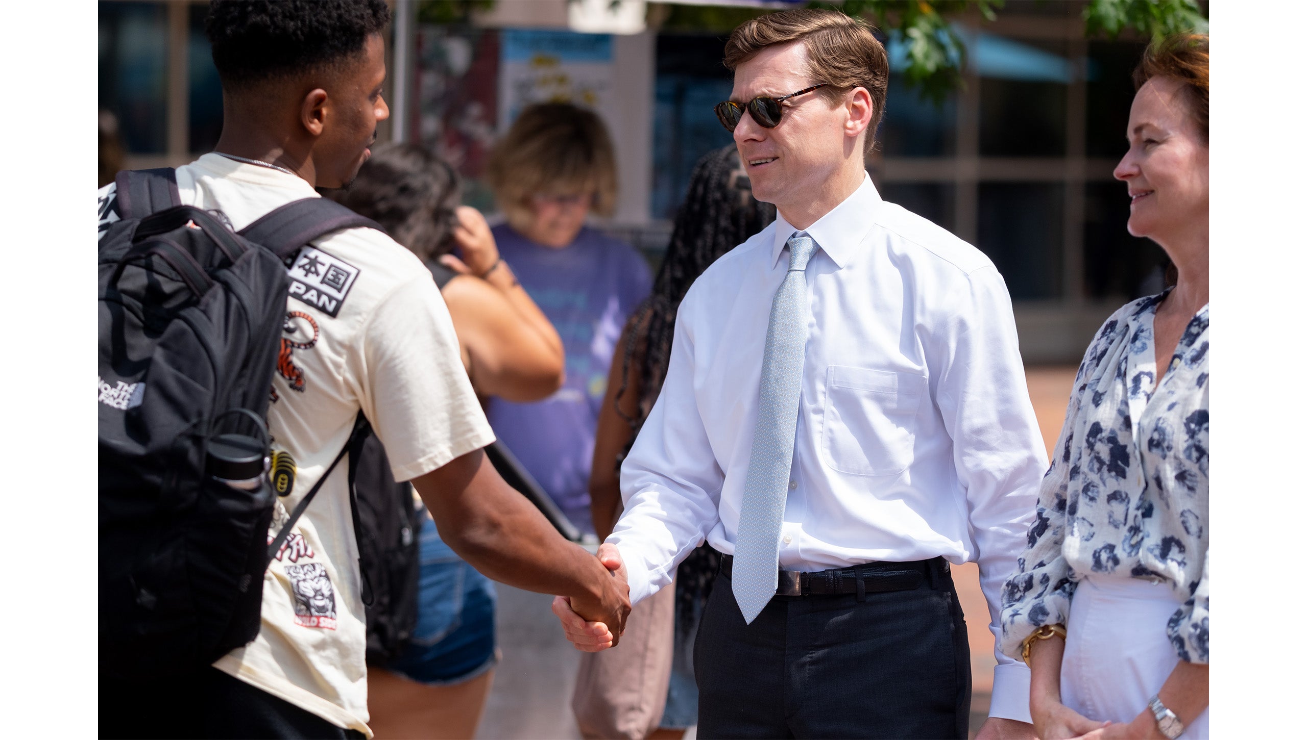 UNC-Chapel Hill student near the Pit shaking hands with Chancellor Lee H. Roberts, whose wife, Liza, is standing beside him.