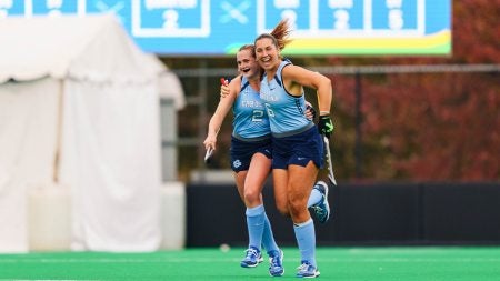 Two Carolina field hockey players, Charly Bruder and Coco Courtright, hugging and celebrating during the ACC championship game.