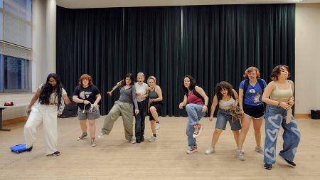 Nine students in a rehearsal studio, practicing choreography.