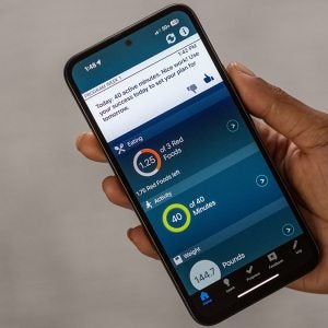 A hand holding a phone with the weight metrics pulled up on the screen.