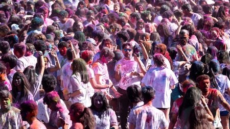 Crowd of students on a field celebrating Holi