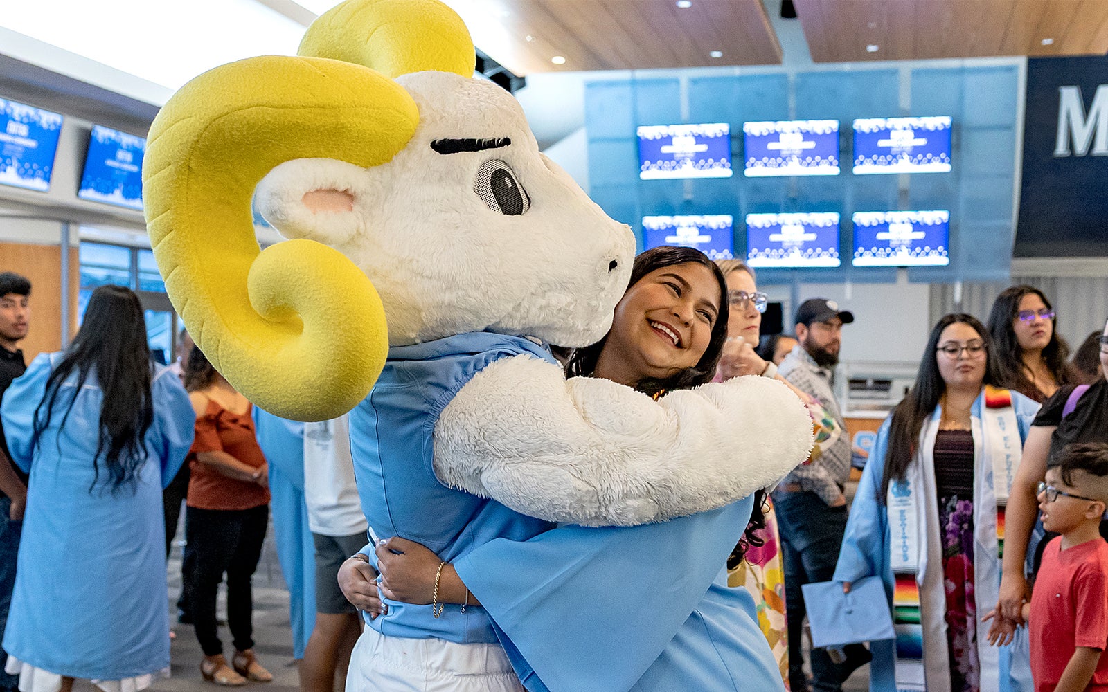 Rameses hugs a graduate at the Exitos Graduation Ceremony in May 2025 at UNC-Chapel Hill