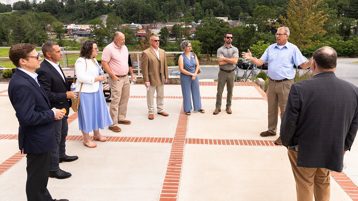 Group of nine people meeting as a group and chatting outside on a sidewalk area in Spruce Pine.