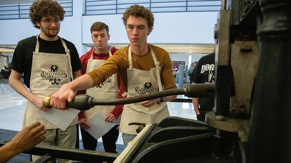 Students work with a printing press from 1884 during a class at Davis Library.