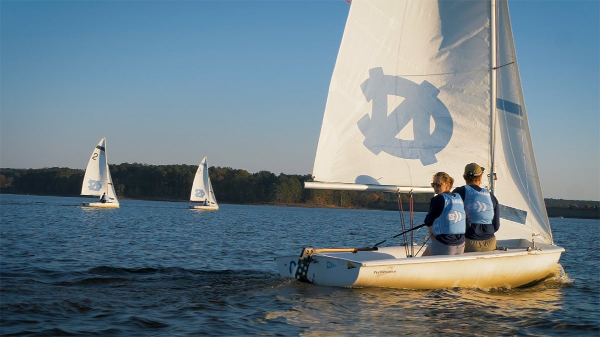 Three sail boats on a lake, all with white sails and the interlocked 