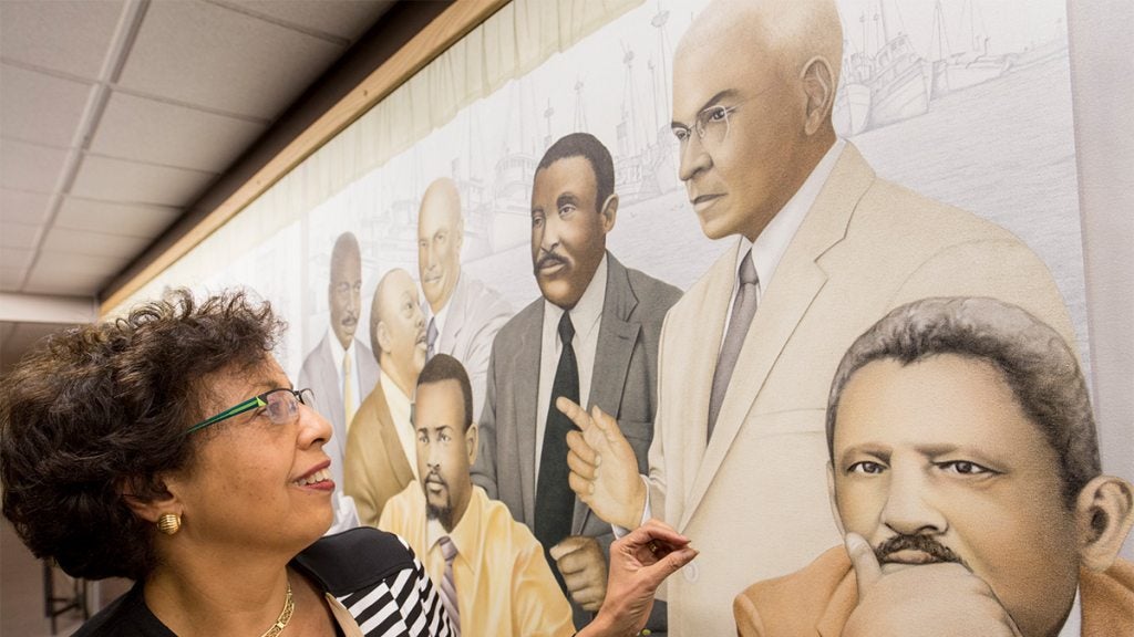 A woman looking at a mural titled "SERVICE"