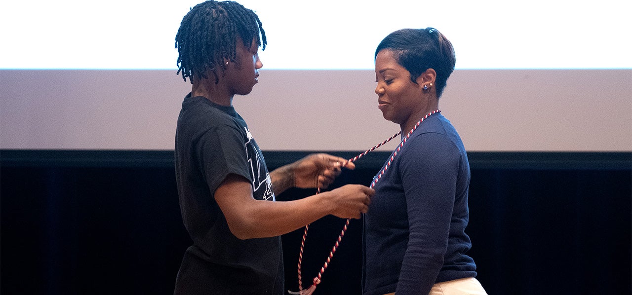 Sheree Stewart on stage with a family member at UNC-Chapel Hill's Red, White and Carolina Blue graduation event.