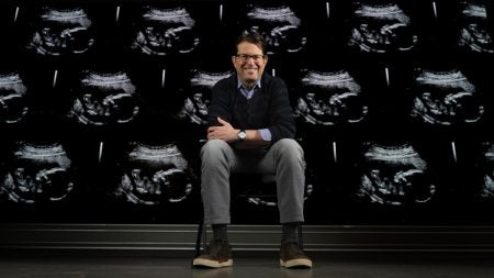 Jeffrey Stringer sitting in front of a wall of ultrasounds.