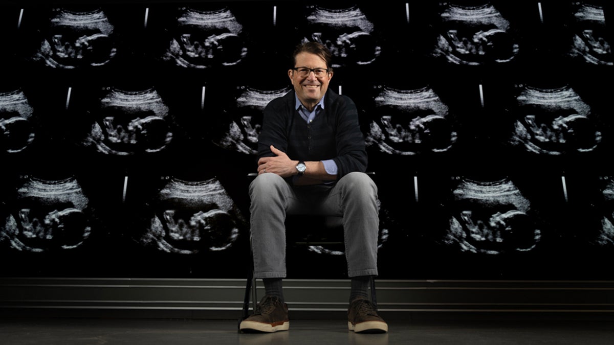 Jeffrey Stringer sitting in front of a wall of ultrasounds.