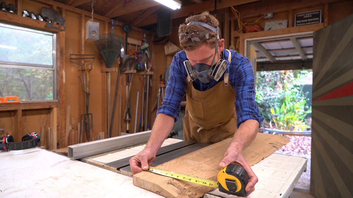A woodworker measures a piece of wood.