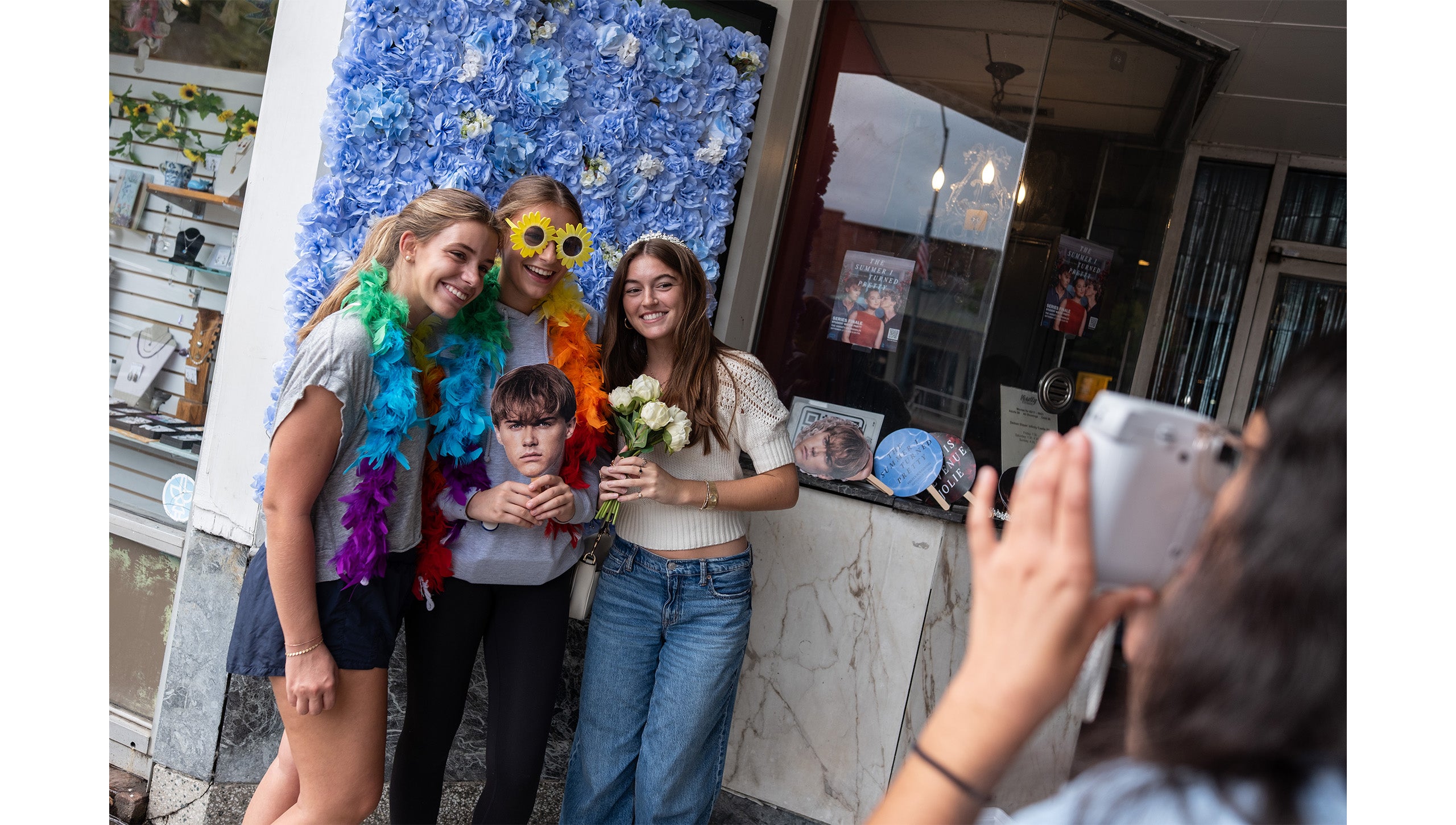 Three UNC-Chapel Hill students holding up head cutouts of characters from “The Summer I Turned Pretty” outside the Varsity Theatre.