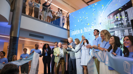 Crowd applauding in front of Bell Hall poster.
