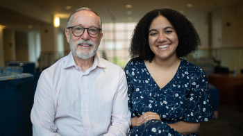 Two people sit together smiling in a bright lounge - scholarship alumnus Dan Dalton and current student Kassidy Johnson.”