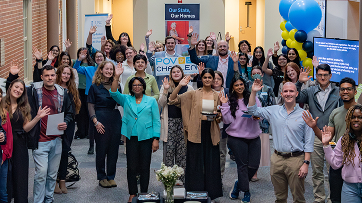 Students and faculty gathered in room waving at camera.