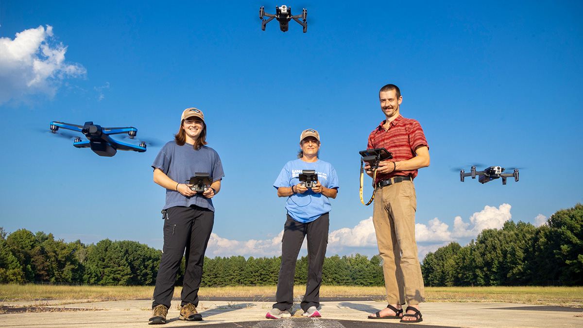 Three individuals piloting drones.