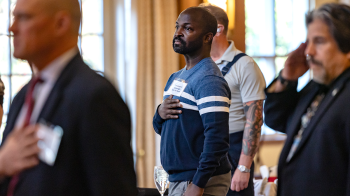 Christopher Genwright standing for the national anthem amongst other attendees.