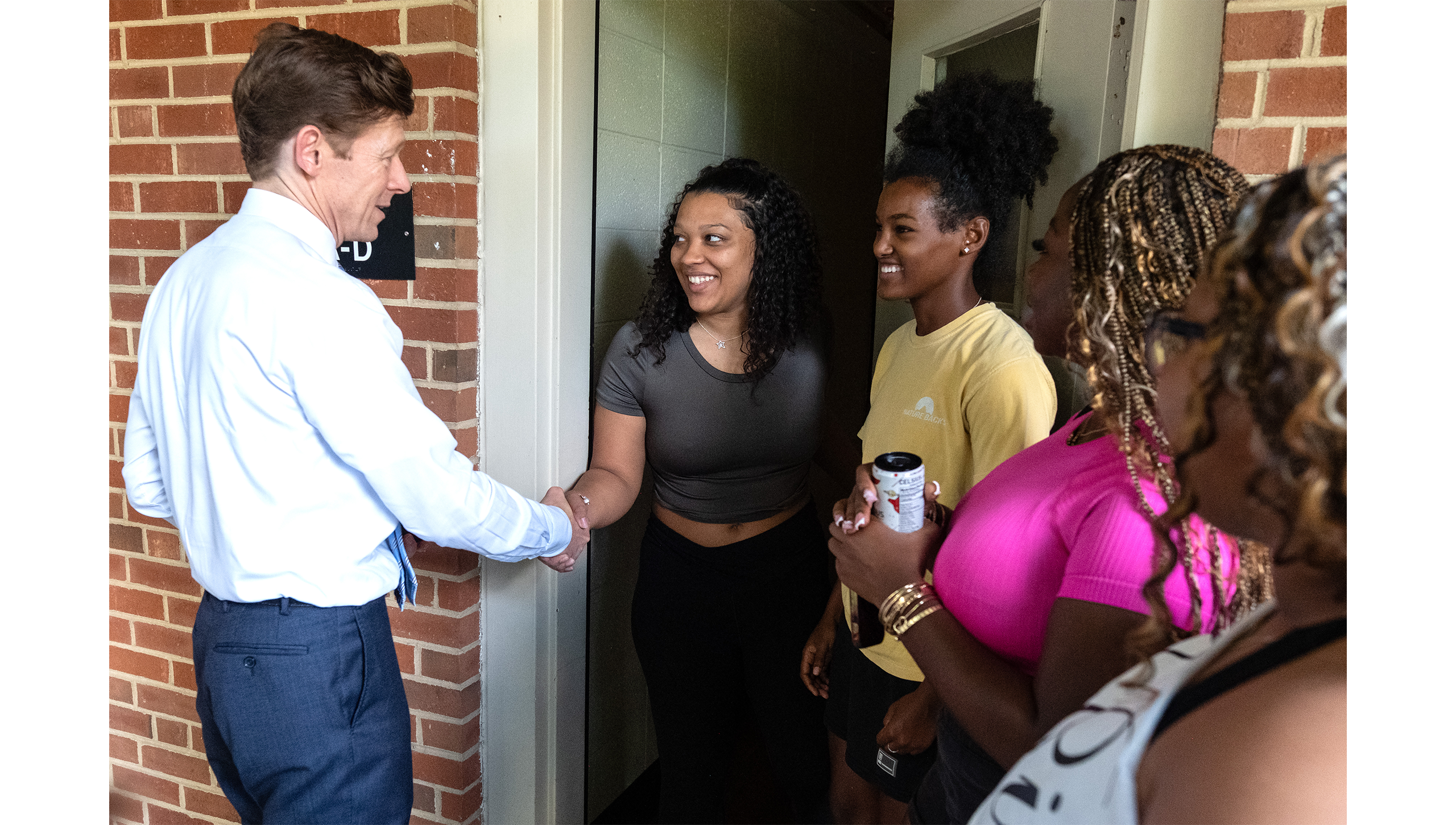 Chancellor Roberts shaking hands with students outside of dorm room.