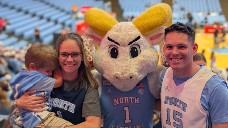 A family photo of Erin Mathis' on the right, and his wife hold his son with the character mascot Rameses from U.N.C. Chapel Hill.